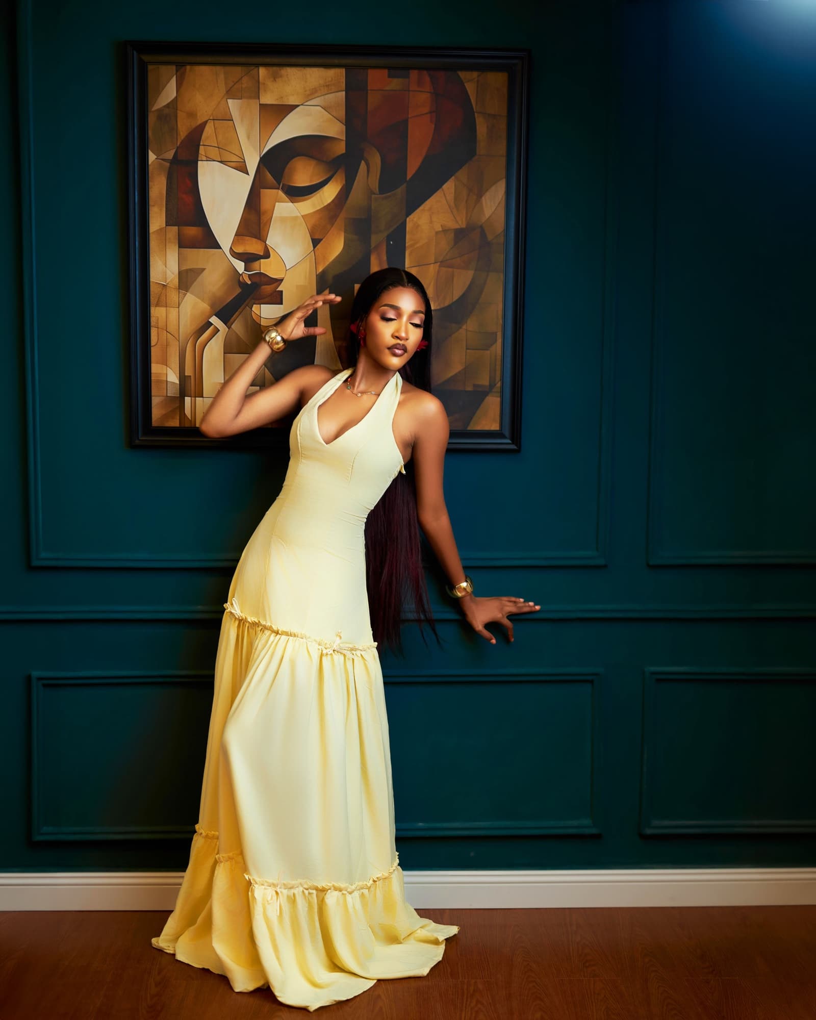 Bluethopia in a butter yellow dress leaning against a teal panelled wall