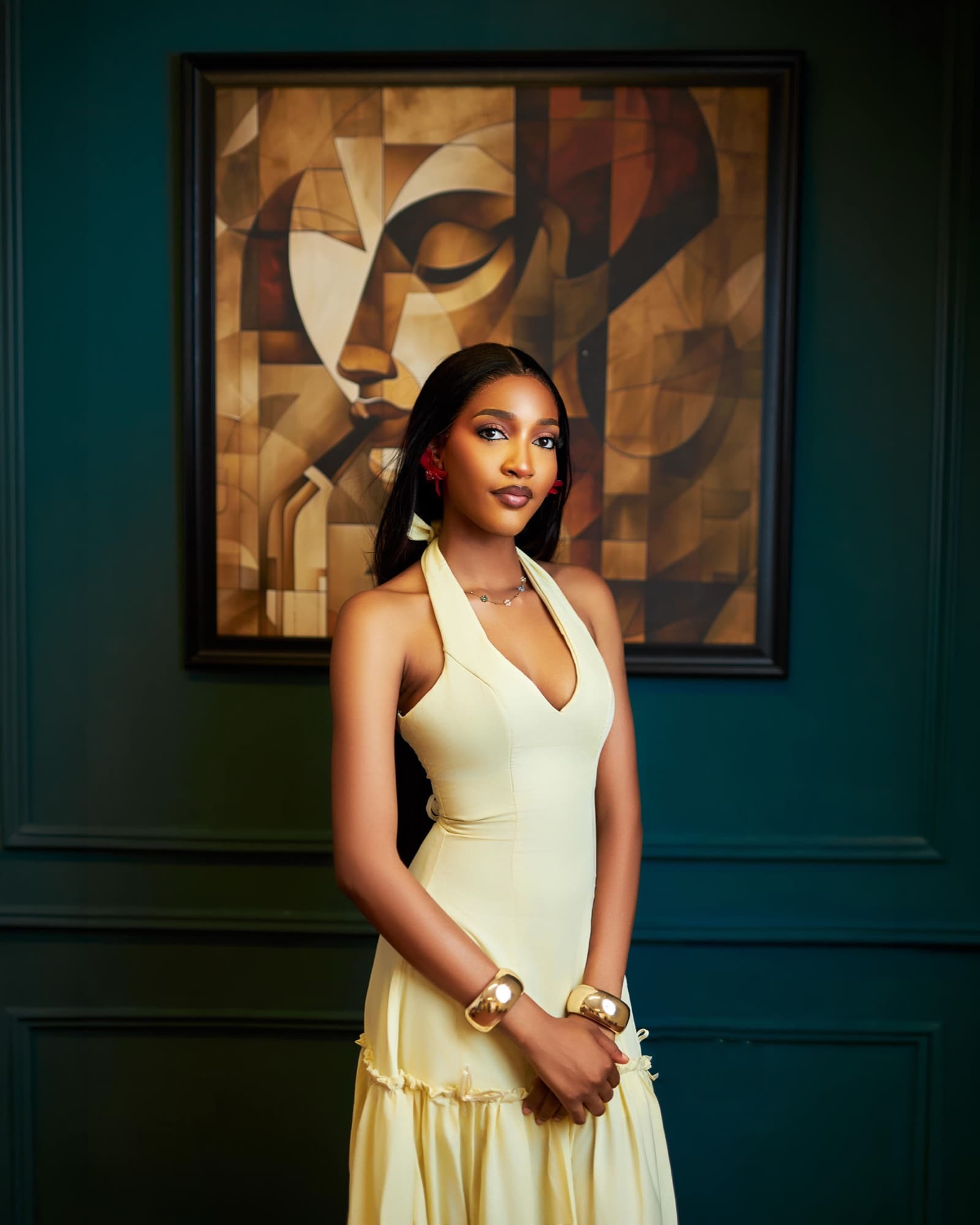 Butter yellow halter dress in front of an abstract painting
