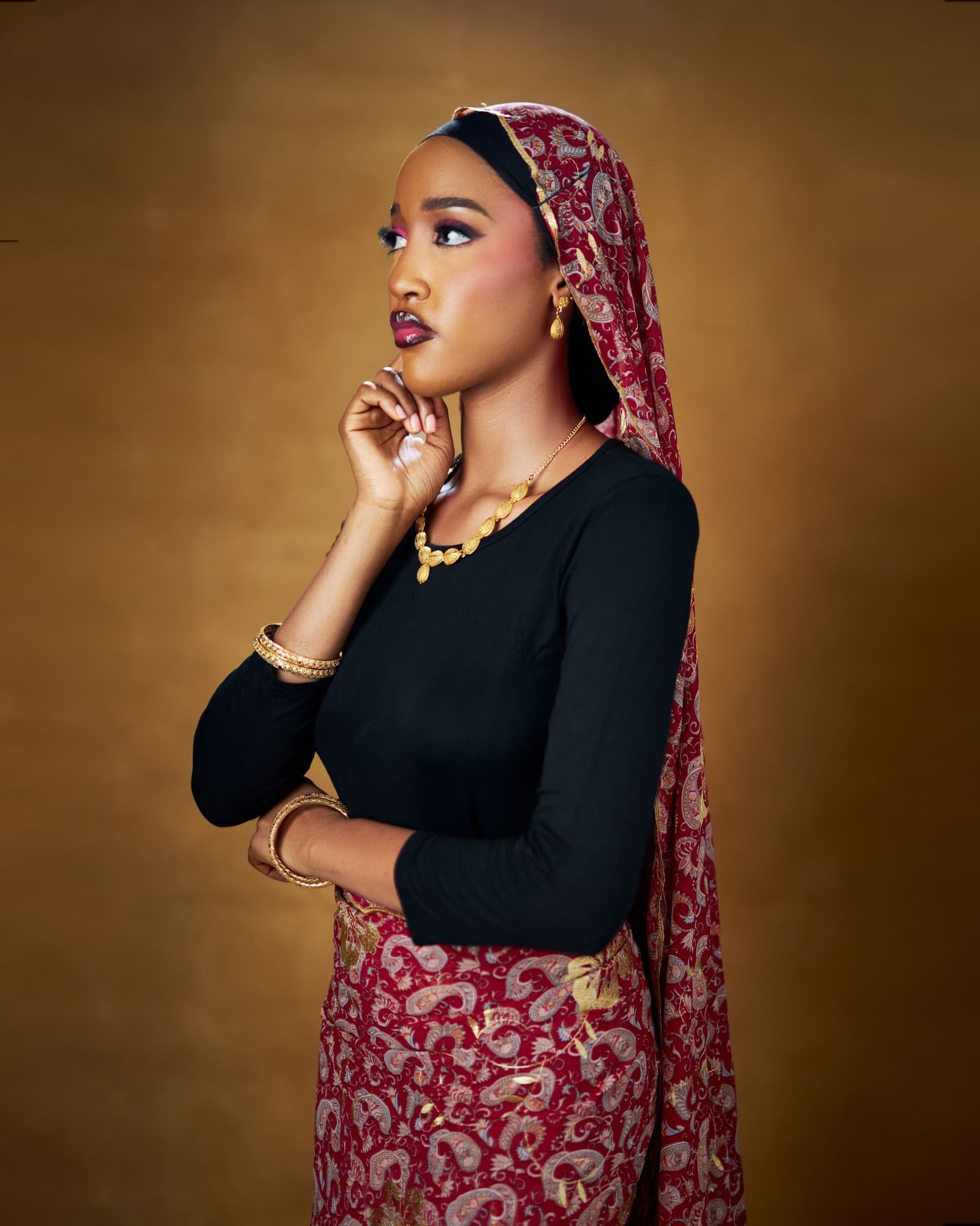 Bluethopia in a red and gold paisley veil, hand resting at her chin