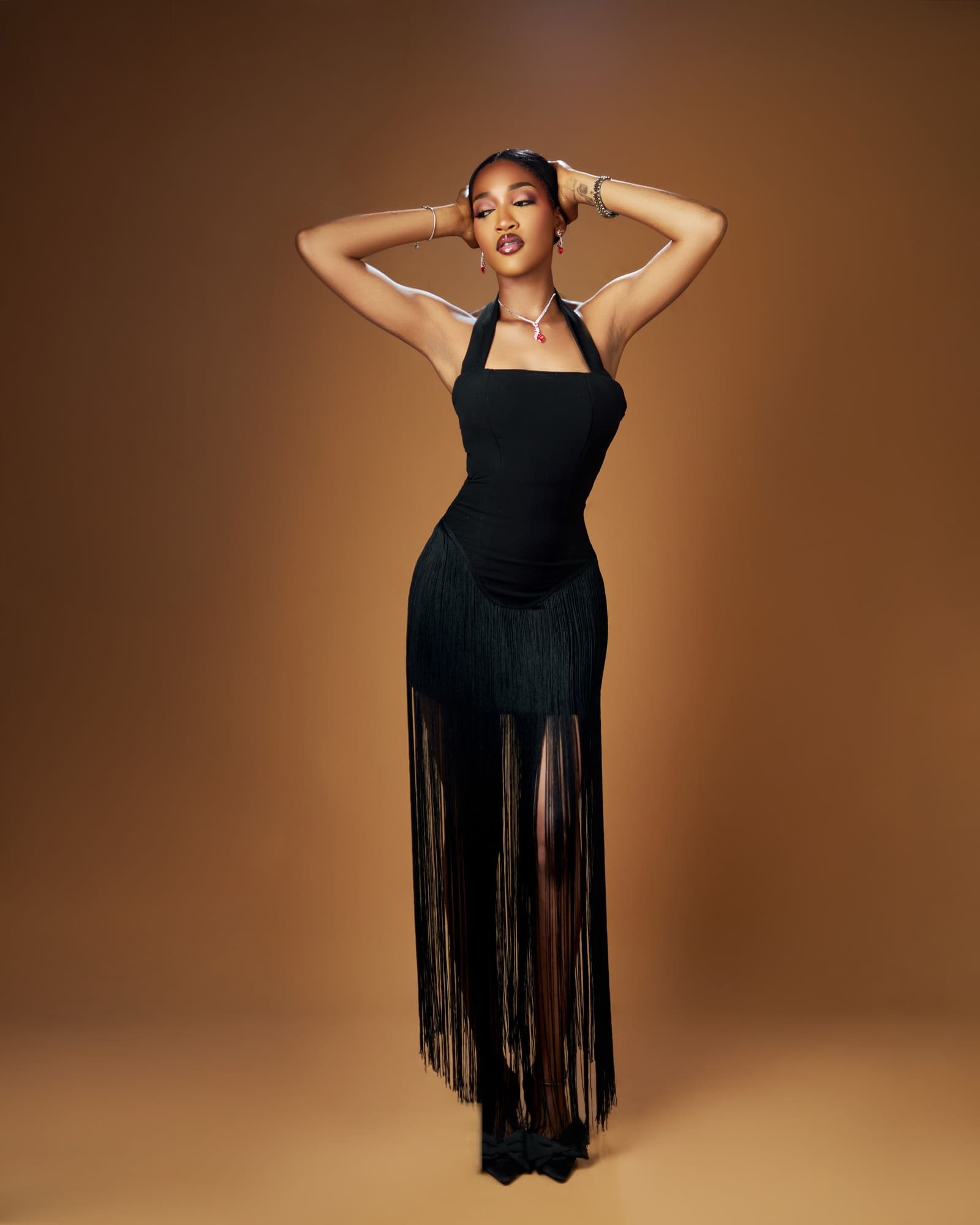 Bluethopia in a black fringe dress, hands behind her head