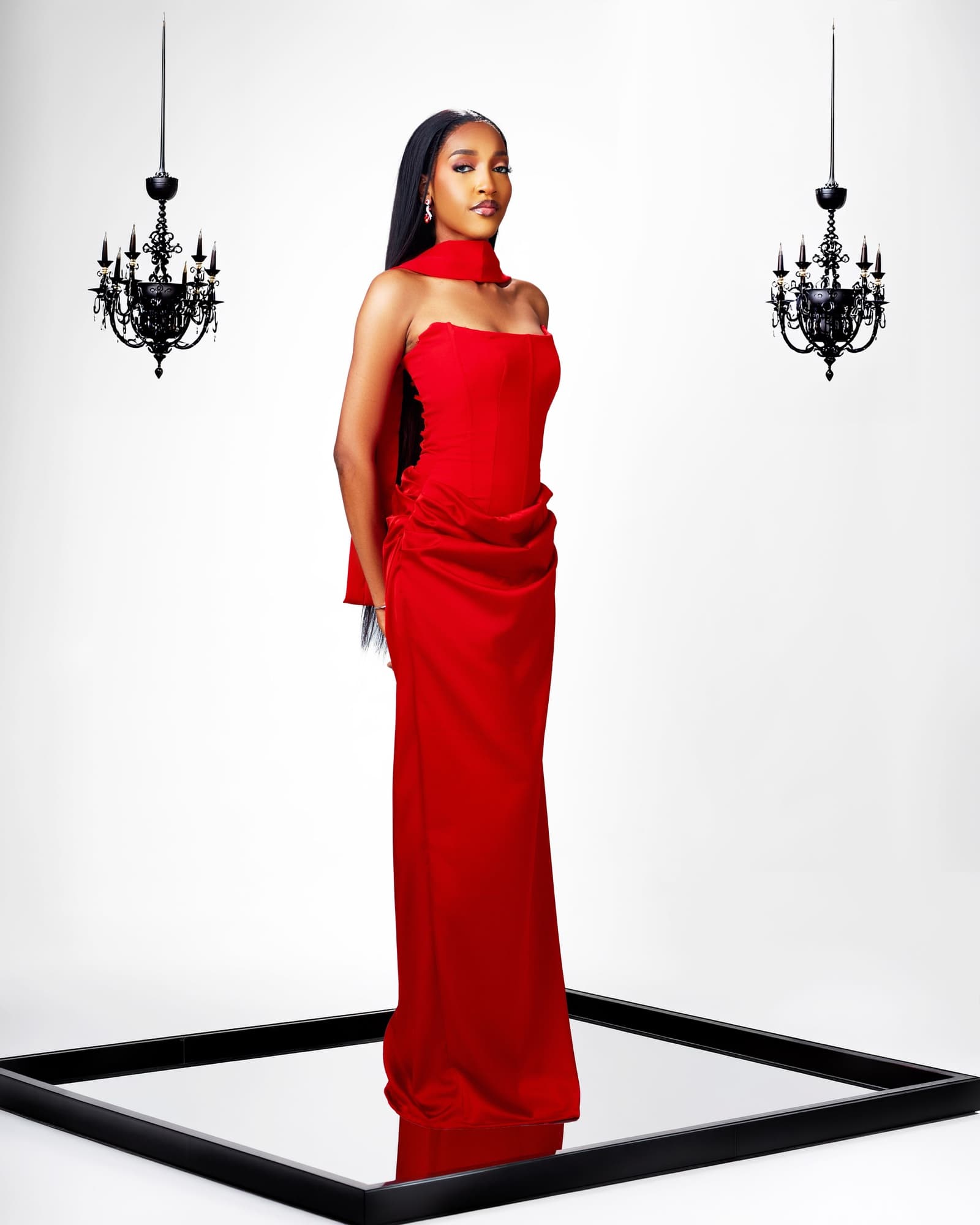 Red column gown between two black chandeliers